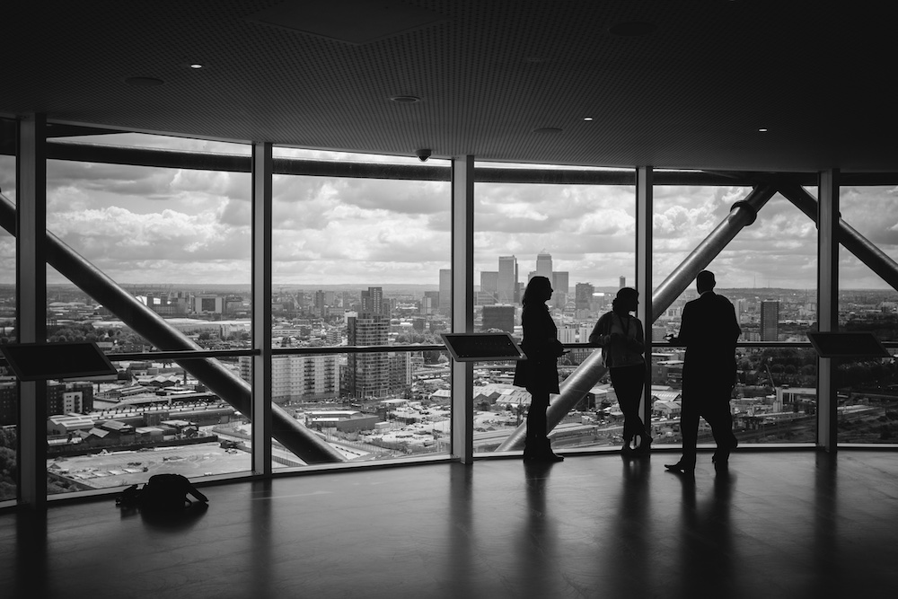 Hall overlooking city with 3 people talking in a tall building.